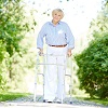 Image d'une femme âgée se promenant dans un park avec un déambulateur