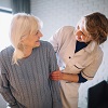 Image d'une femme âgée souriante à la maison avec un prestataire d’aide à domicile