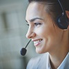 Image d'une interlocutrice souriante avec un casque répondant aux questions d'un senior et des familles sollicitant un service d'aide